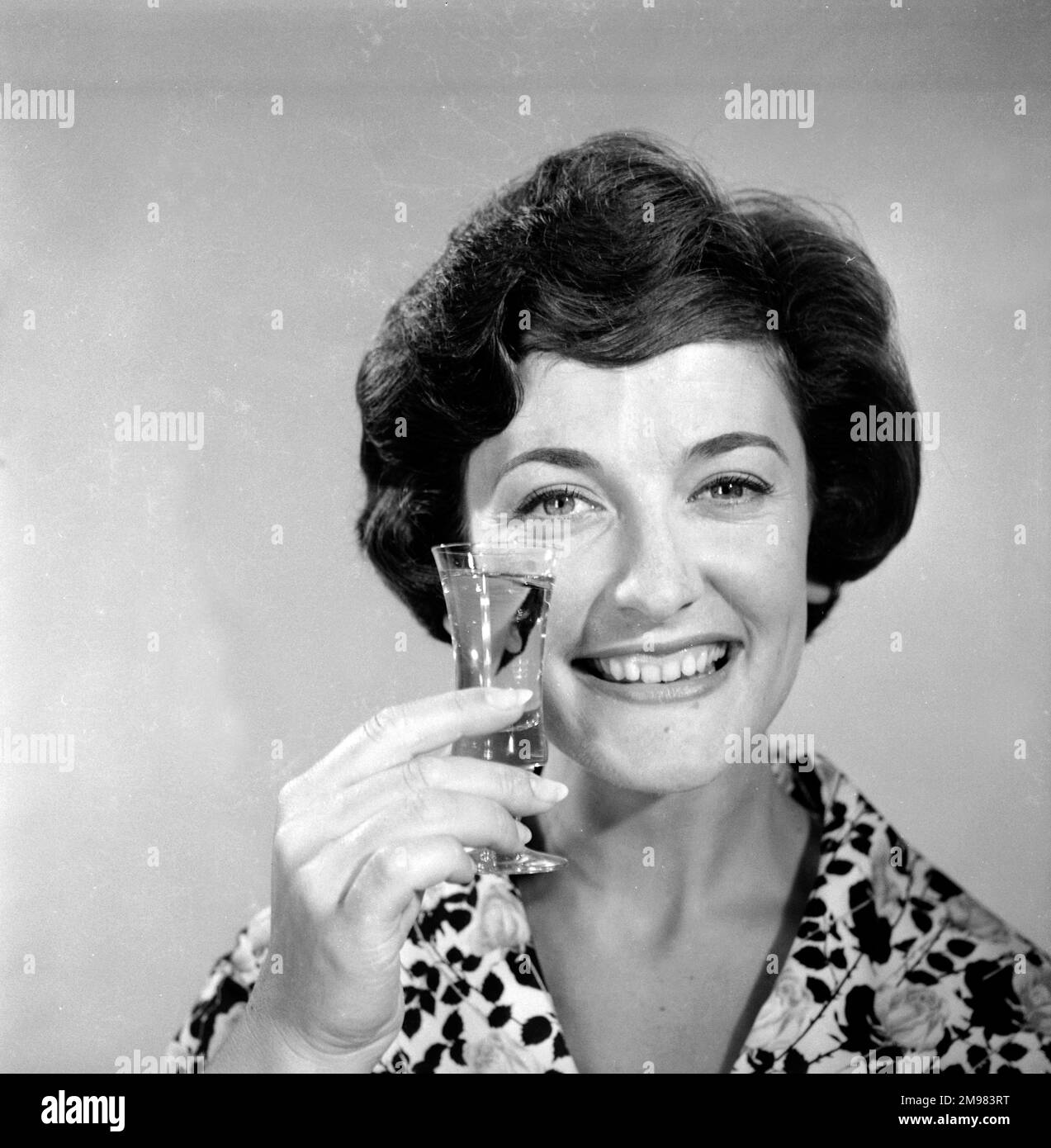 Pubblicità per lo sherry dell'emu -- modello femminile sorridente (Yvonne Marsland) che tiene su un vetro. Foto Stock