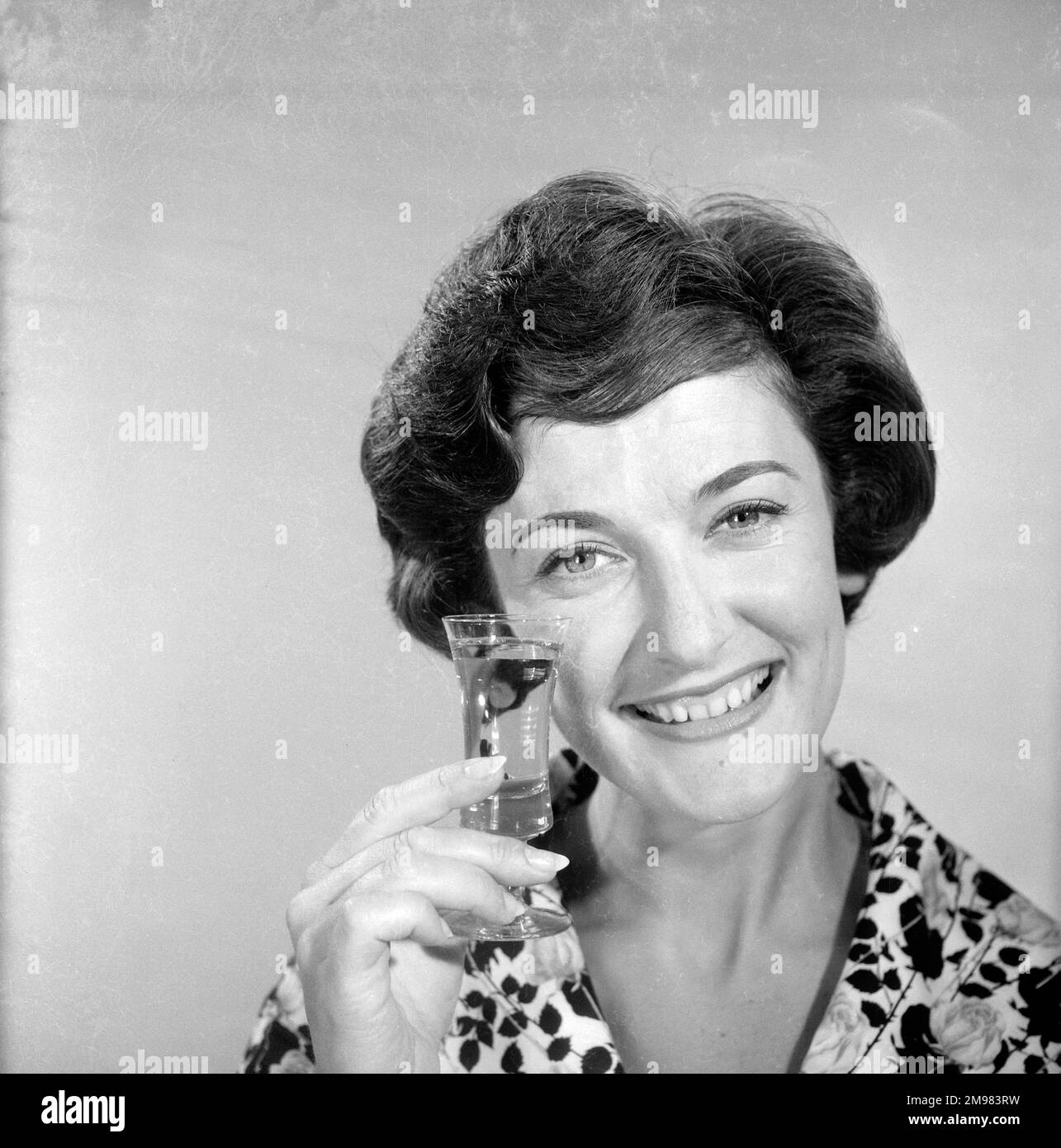 Pubblicità per lo sherry dell'emu -- modello femminile sorridente (Yvonne Marsland) che tiene su un vetro. Foto Stock
