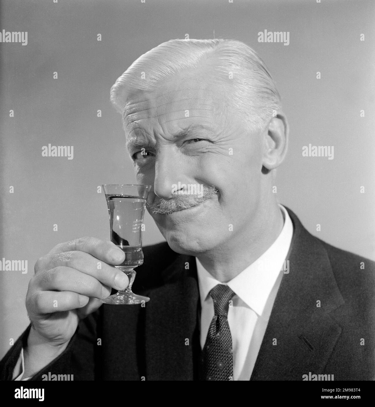 Pubblicità per lo sherry dell'emu -- modello maschio sorridente (George McGrath) che tiene su un vetro. Foto Stock