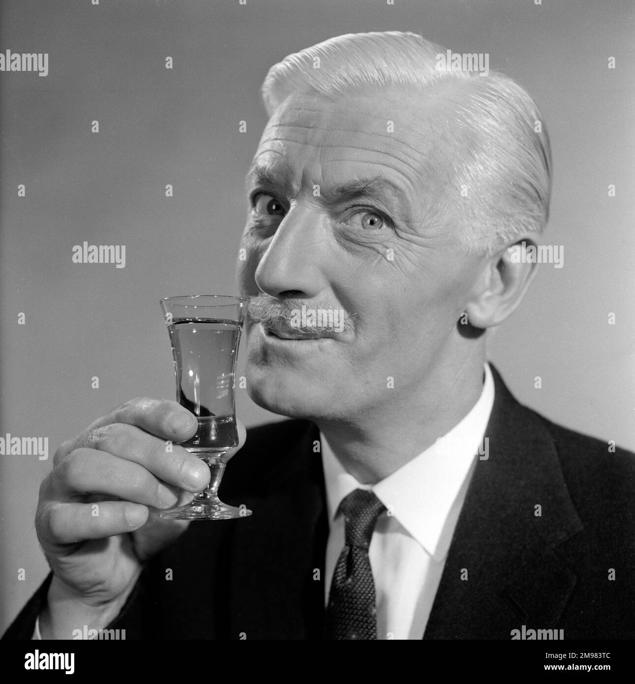 Pubblicità per lo sherry dell'emu -- modello maschio sorridente (George McGrath) che tiene su un vetro. Foto Stock