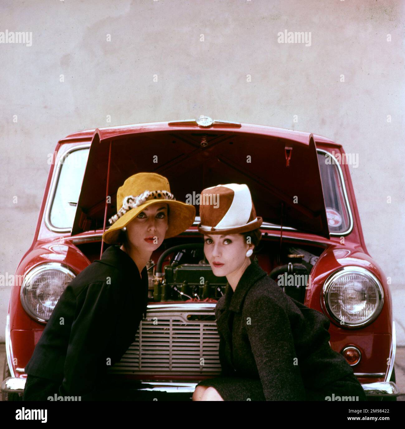 Tatler cover photoshoot focalizzato su cappelli e il Motor Show - due modelli femminili in posa di fronte a una Mini auto rossa. Una variante di ripresa di questo particolare photoshoot è stata utilizzata per la copertina del numero Tatler per il 21 ottobre 1959 (vedi immagine 11064837). Foto Stock