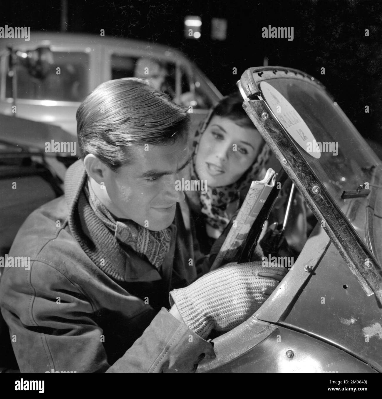 Pubblicità per i prodotti per capelli Silvikrin -- modelli maschili e femminili (Peter Christian e Anne Cave) in una scena di rally auto. Foto Stock