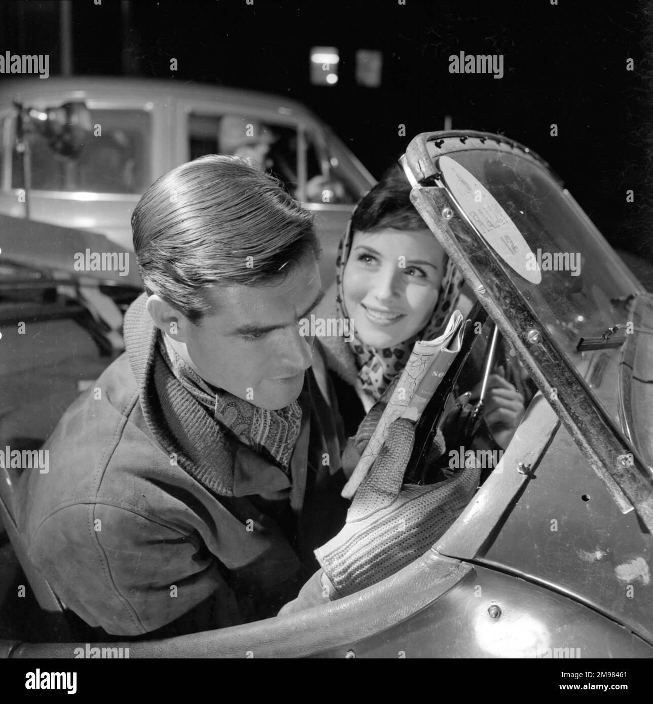 Pubblicità per i prodotti per capelli Silvikrin -- modelli maschili e femminili (Peter Christian e Anne Cave) in una scena di rally auto. Foto Stock