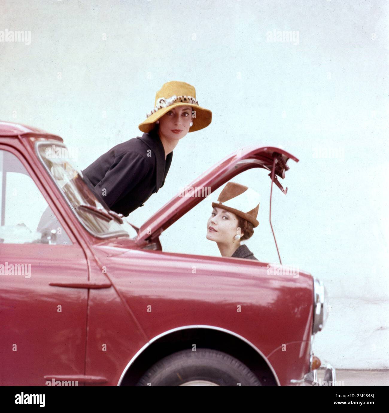 Tatler cover photoshoot focalizzato su cappelli e il Motor Show - due modelli femminili in posa con una mini auto rossa. Una variante di ripresa di questo particolare photoshoot è stata utilizzata per la copertina del numero Tatler per il 21 ottobre 1959 (vedi immagine 11064837). Foto Stock