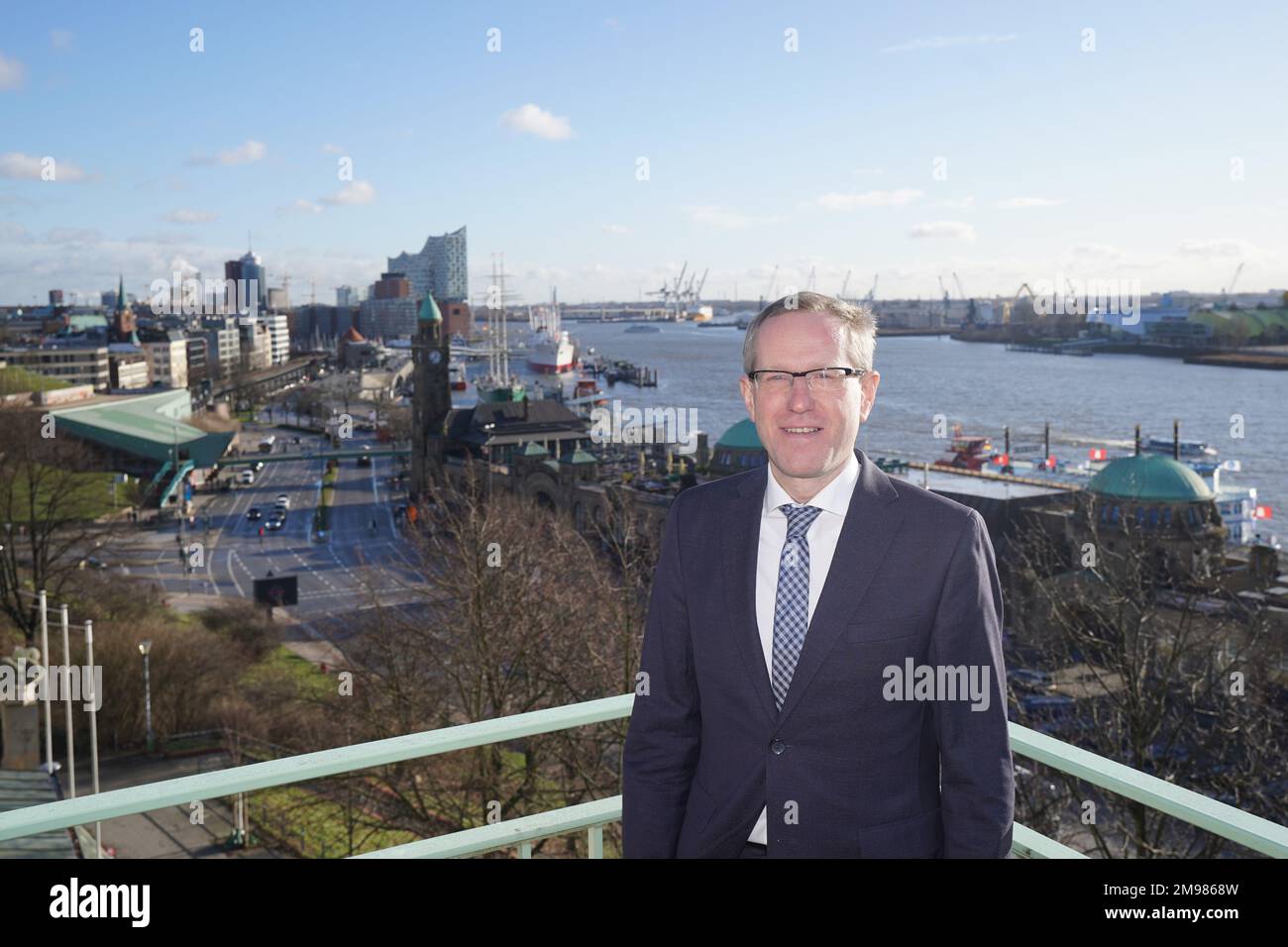 17 gennaio 2023, Amburgo: Thomas Dehling, capo del Dipartimento idrografia nautiche, si trova su un balcone dopo la conferenza stampa annuale dell'Agenzia federale marittima e idrografica (BSH). Sullo sfondo si possono vedere il Landungsbrücken, il Überseebrücke e l'Elbphilharmonie. La BSH non vede alcuna possibilità di accelerare il processo di approvazione del dumping del limo Elbe nella zona economica esclusiva. Amburgo è sotto una certa pressione quando si tratta di smaltimento del limo, perché l'accordo sullo scarico del limo in mare marker E3 nei pressi di Helgoland è limitato nel tempo e nei paesi vicini di SCH Foto Stock