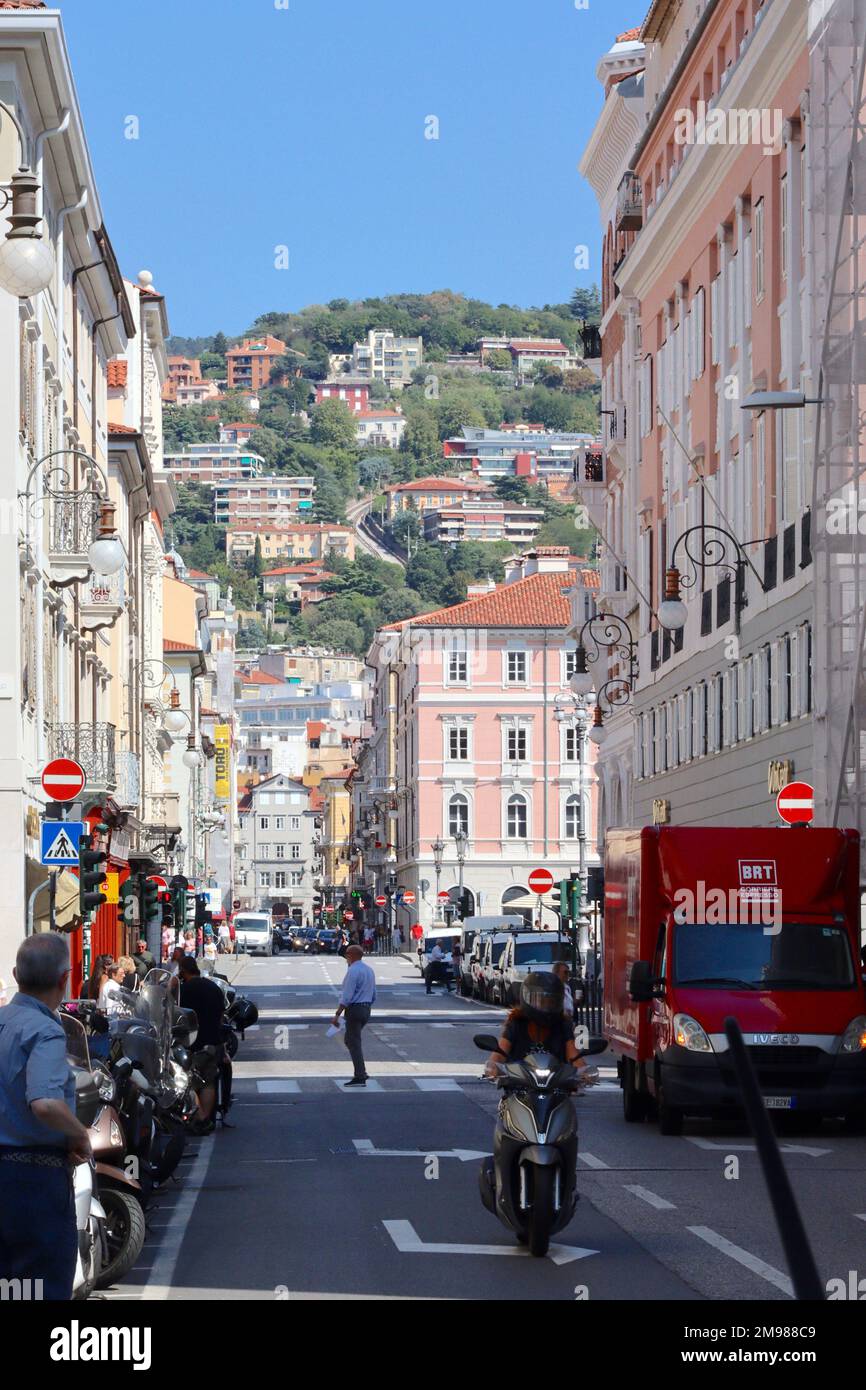 Guardando verso nord-est lungo la Via Roma, Trieste, Italia, durante un breve periodo di noia nel traffico che si svolge al semaforo. Foto Stock