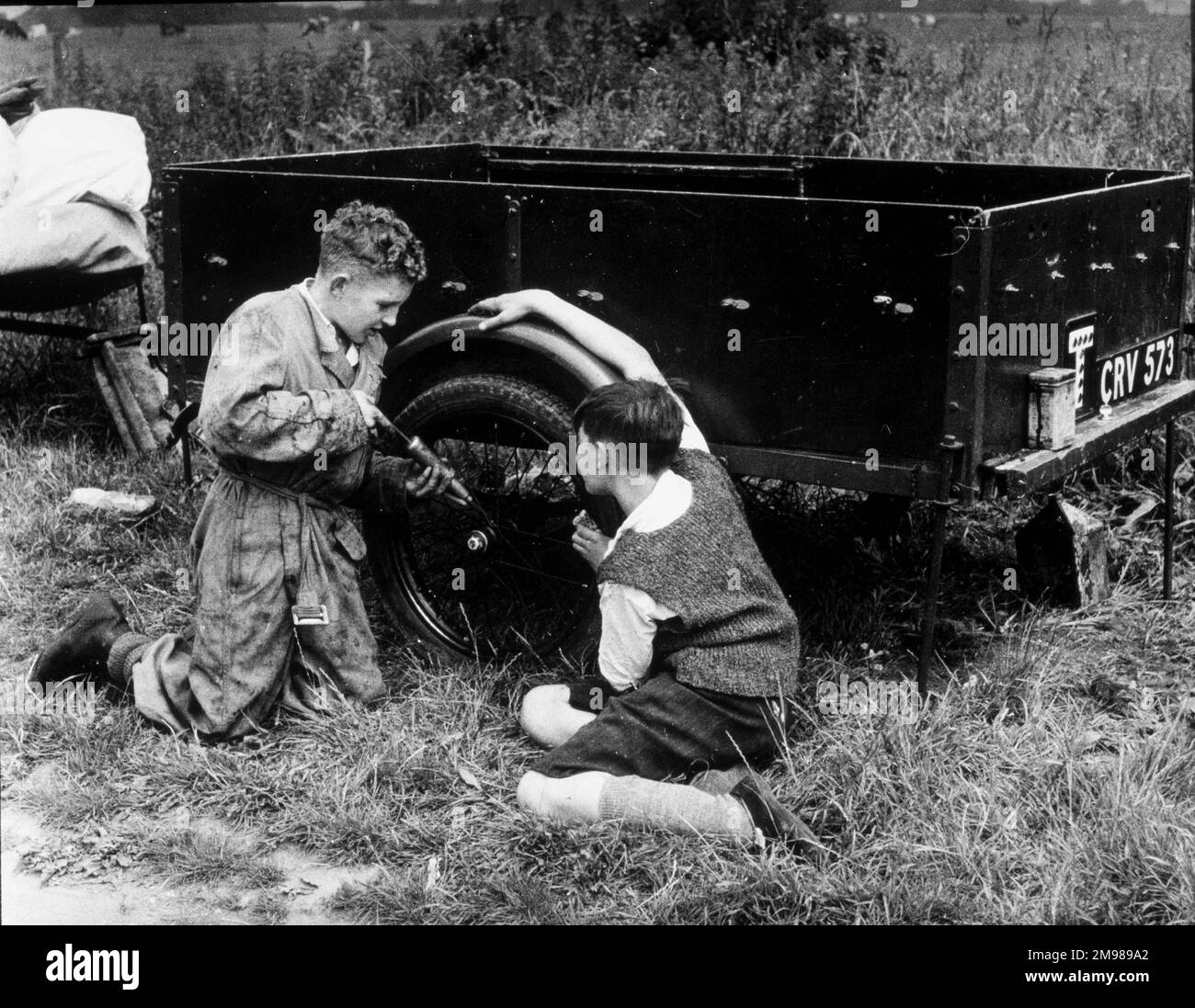 Due ragazzi che riparano un rimorchio, probabilmente utilizzati per un viaggio in scouting o in campeggio. Foto Stock