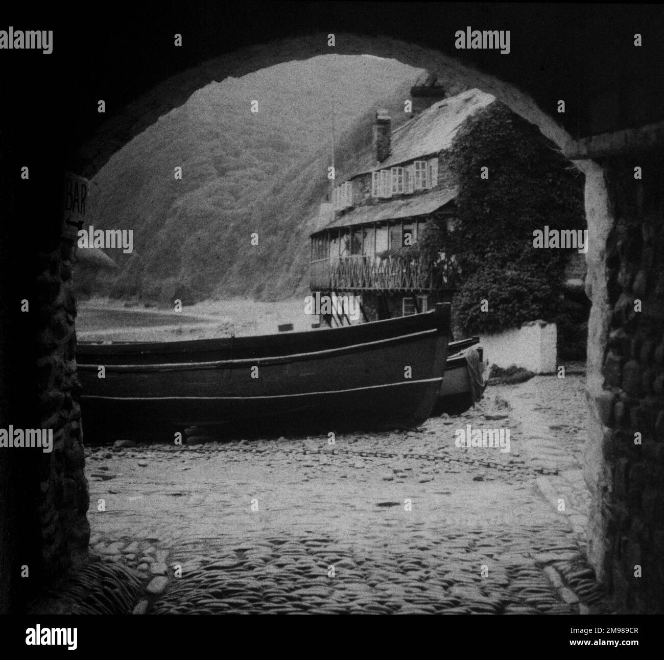 Barca su un scivolo con cottage sul mare sullo sfondo, visto attraverso un arco. Foto Stock