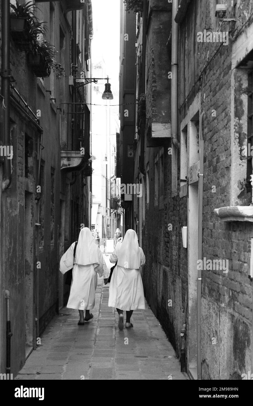 Le monache camminano lungo uno stretto passaggio a Venezia. Foto Stock