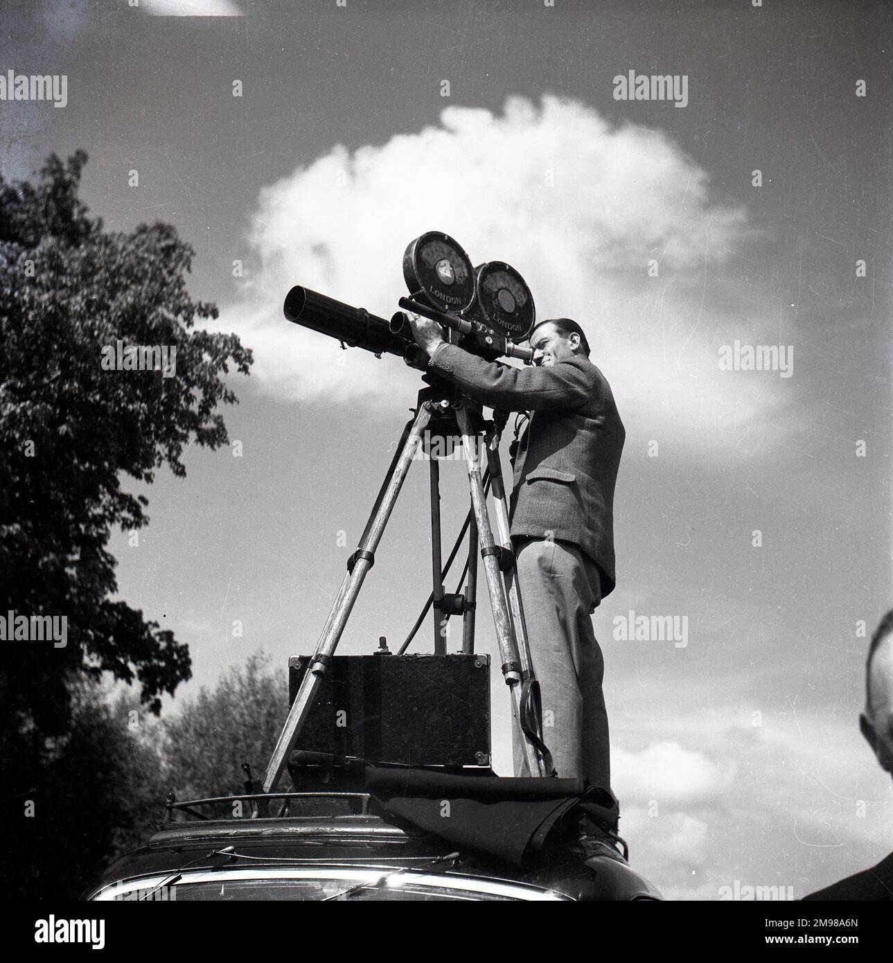 Il cameraman del newsreel in azione, filma dall'alto di una macchina. Foto Stock