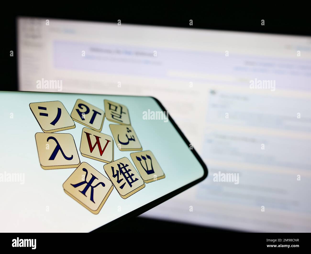 Smartphone con il logo del dizionario online Wikizionario (Wikimedia) sullo schermo di fronte al sito web. Messa a fuoco al centro a sinistra del display del telefono. Foto Stock