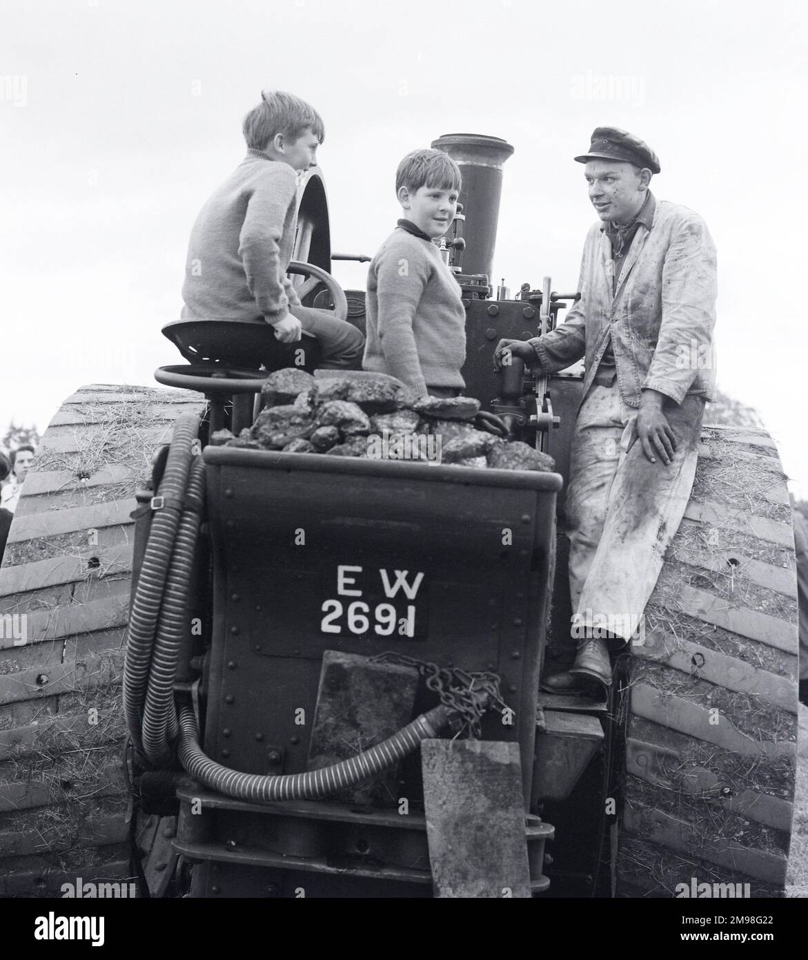 Due ragazzi con un uomo che indossa il cappuccio e le soprabiti su un motore Traction mentre si trova in una fiera del Gloucestershire Inghilterra Foto Stock