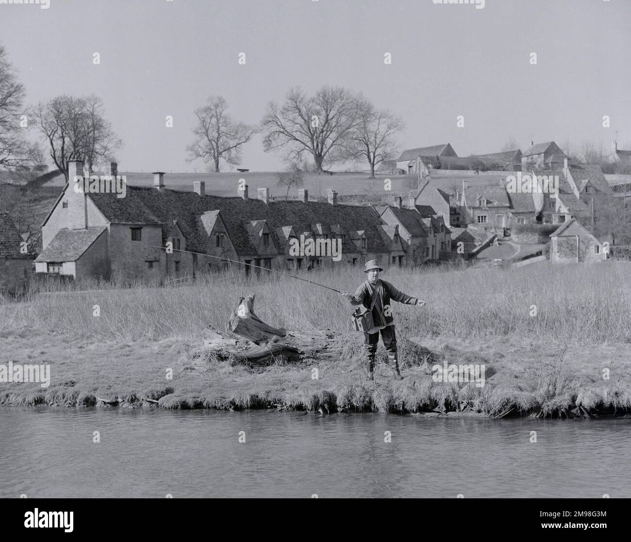 Pesca del pescatore della mosca nel Coln Bibury Gloucestershire Inghilterra Arlington Row Cottages sullo sfondo Foto Stock