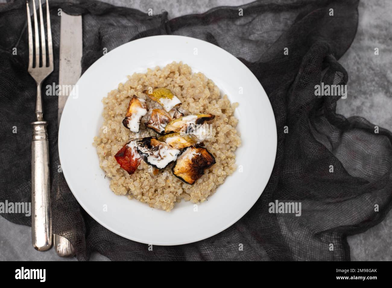 Quinoa cotta con verdure e salsa su piatto bianco Foto Stock