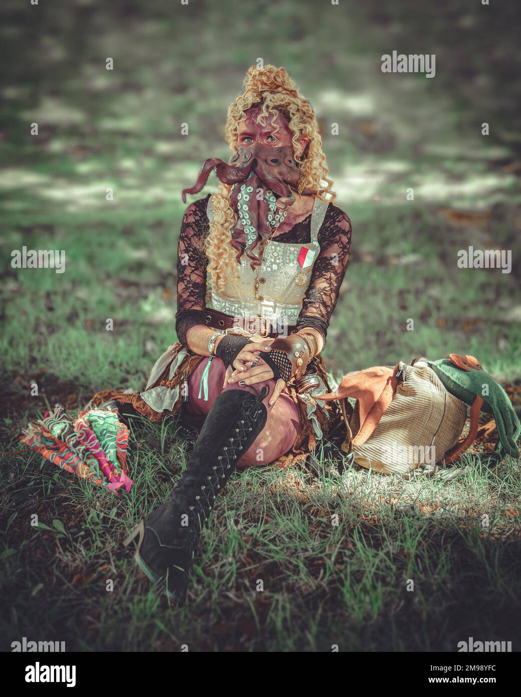 Una strana donna steampunk guardare seduto su erba, ha un polpo attaccato al suo viso. Foto Stock