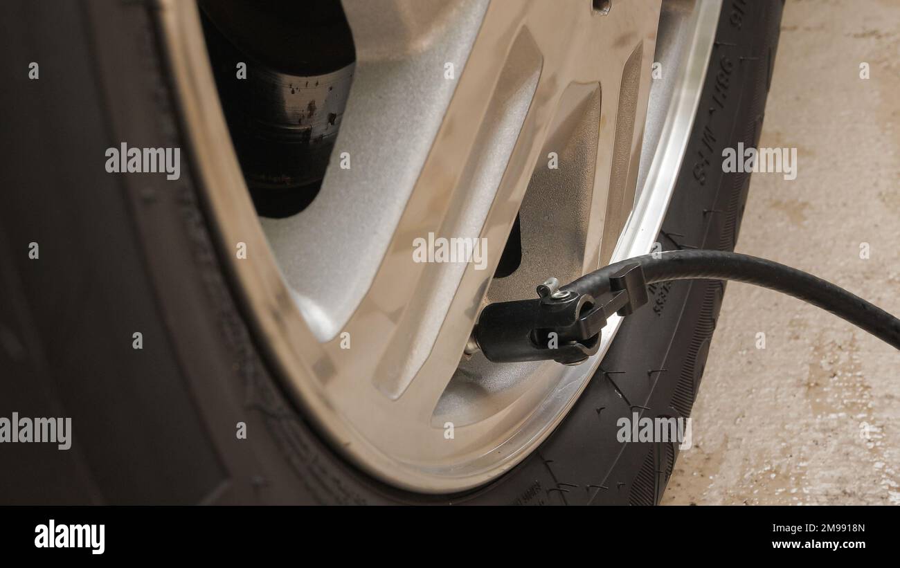 Chiusura dell'ugello di gonfiaggio del compressore dell'aria sullo stelo della valvola di uno pneumatico per auto. Gonfiaggio degli pneumatici per auto alla pressione dell'aria corretta. Foto Stock
