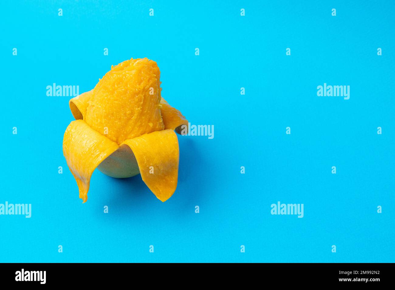 Mango sbucciato con sfondo blu e spazio copia Foto Stock