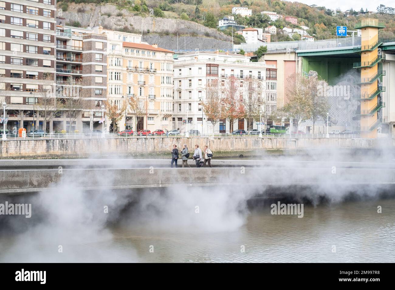 Guardando attraverso il fiume Nervíon dal Guggenheim Bilbao, con la scultura di nebbia #08025 (F.O.G.) di Fujiko Nakaya visibile in primo piano e costruita Foto Stock