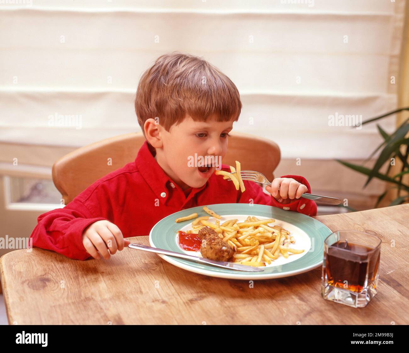 Giovane ragazzo che mangia pollo fritto e patatine fritte, Winkfield, Berkshire, Inghilterra, Regno Unito Foto Stock