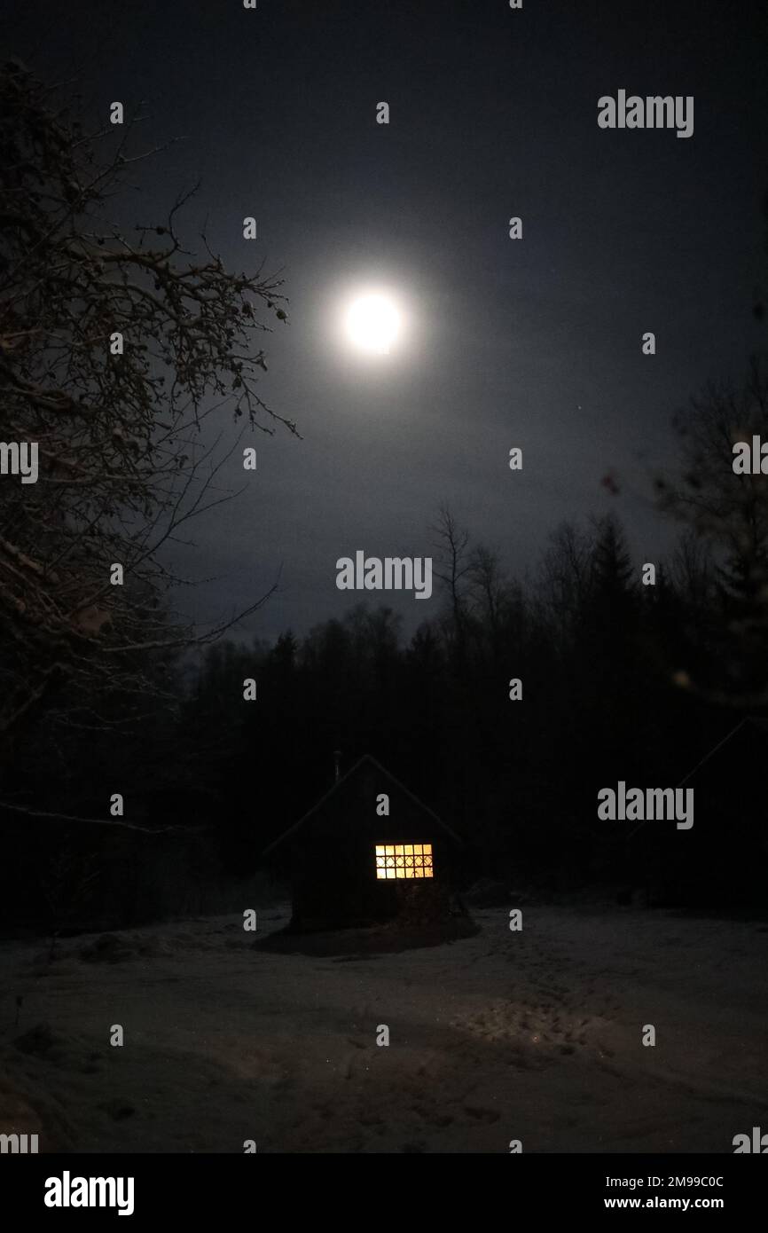 Paesaggio con casa di notte sotto cielo scuro con luna piena. Paesaggio spettrale con casa di notte. Foto Stock