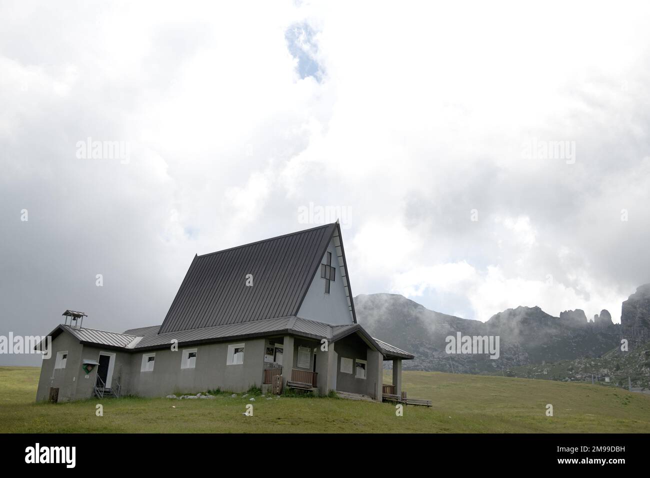 Chiesa cristiana circondata da bianche nuvole sulle Alpi intorno al lago di Como, Lombardia, Italia Foto Stock