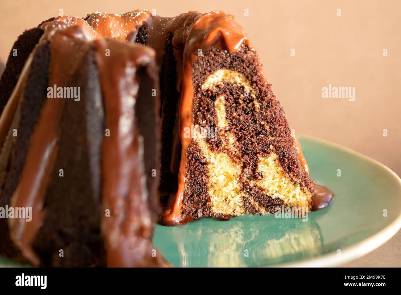 Una torta Bundt marmorizzata al cioccolato e alla vaniglia con un condimento al cioccolato al latte. La torta viene tagliata e placcata Foto Stock
