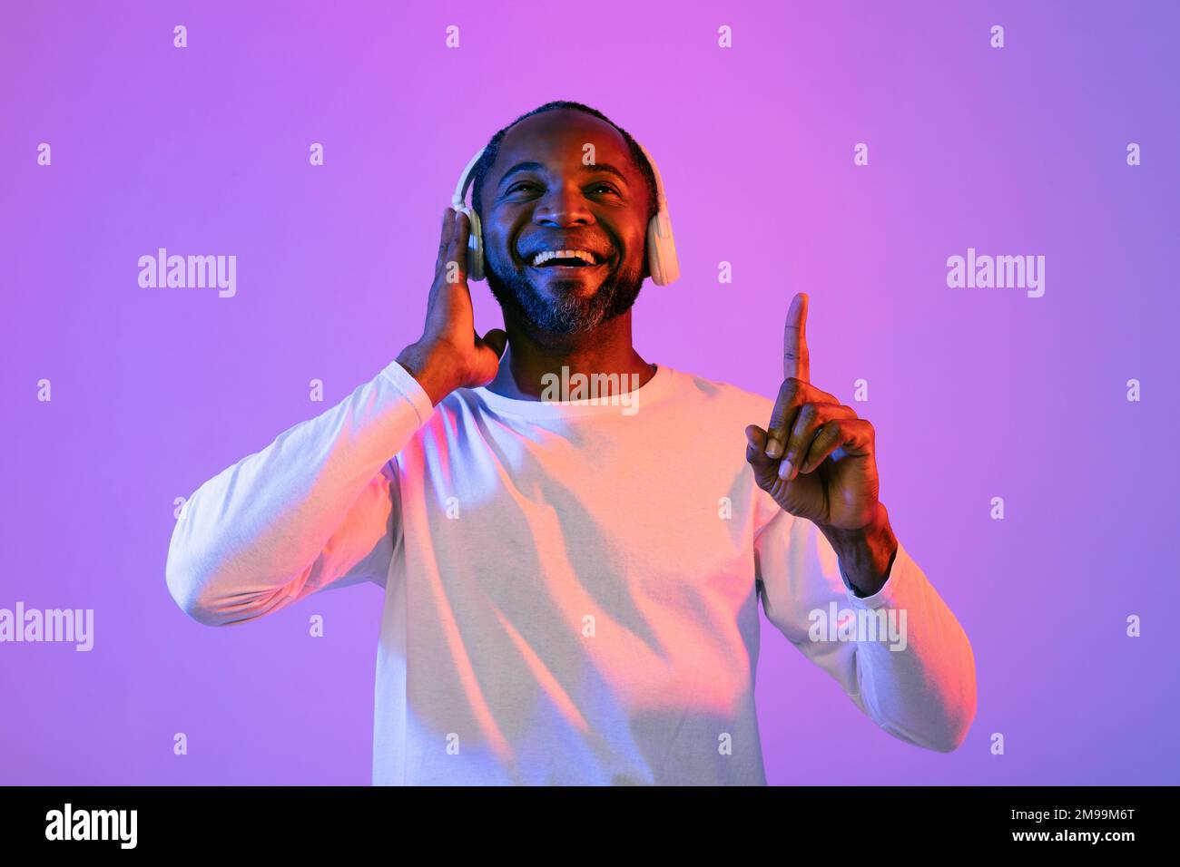 Gioioso uomo nero che ascolta musica e sorridente Foto Stock