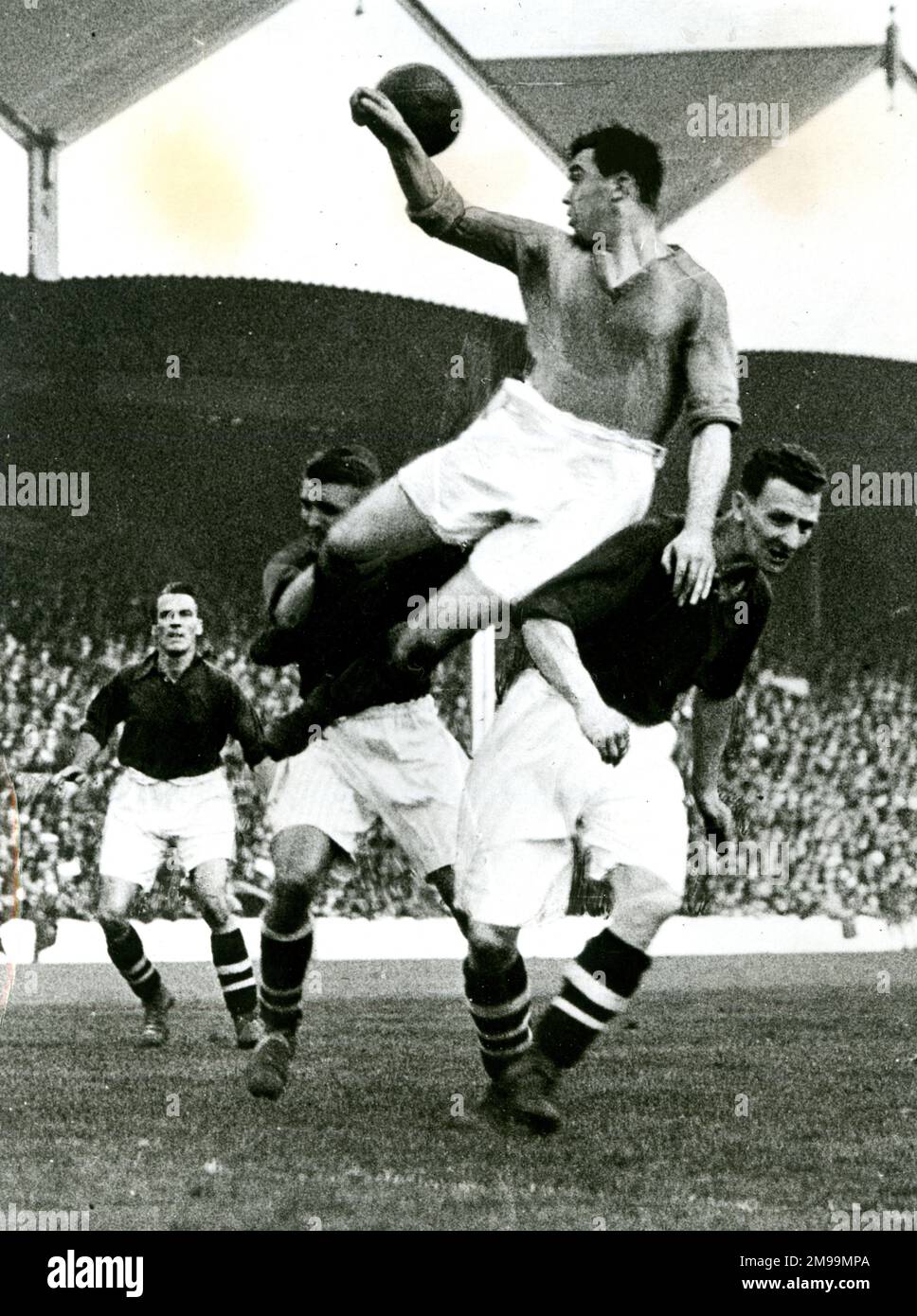 Eddie Hapgood e Herbie Roberts of Arsenal, Dixie Dean of Everton Heading, in una partita di calcio sparata. Foto Stock