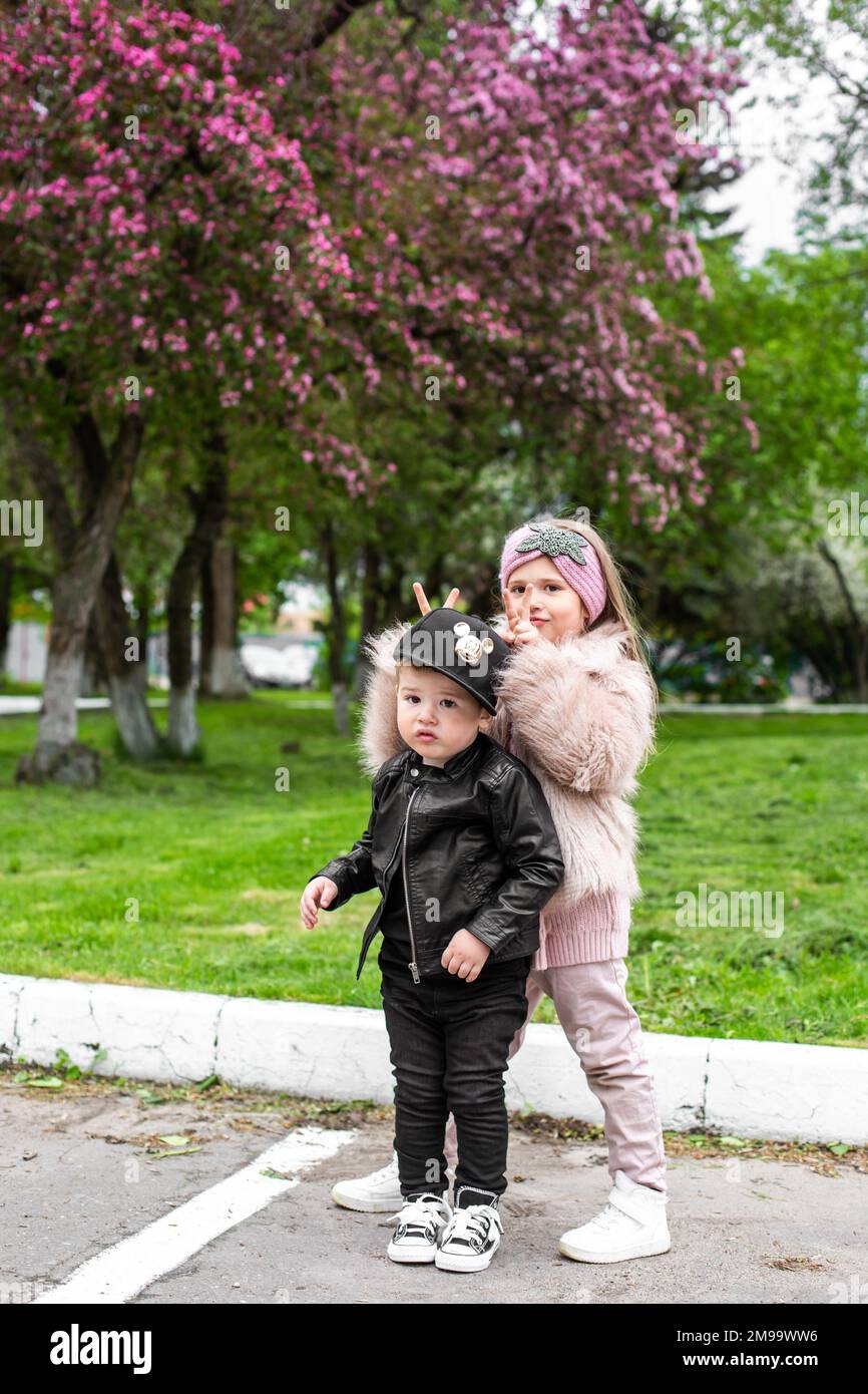 I bambini piccoli cute che giocano insieme nel giardino fiorente dei ciliegi Foto Stock