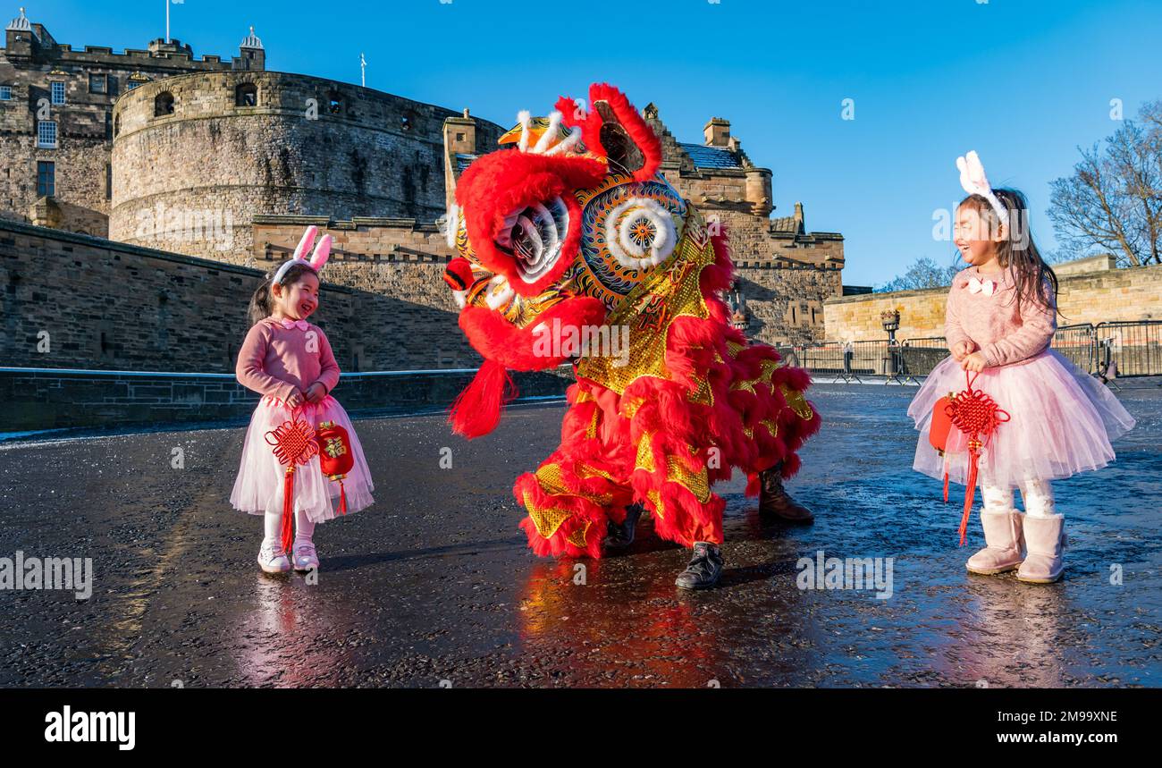 Giovani ragazze cinesi che indossano orecchie di coniglio intrattenuti da danzatori drago per celebrare il Capodanno cinese, (anno del coniglio), Castello di Edimburgo, Scozia, Regno Unito Foto Stock