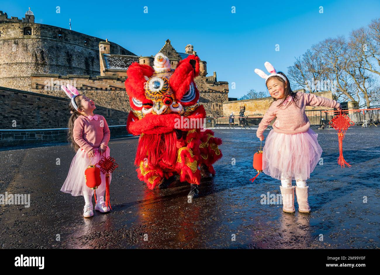 Giovani ragazze cinesi che indossano orecchie di coniglio intrattenuti da danzatori drago per celebrare il Capodanno cinese, (anno del coniglio), Castello di Edimburgo, Scozia, Regno Unito Foto Stock