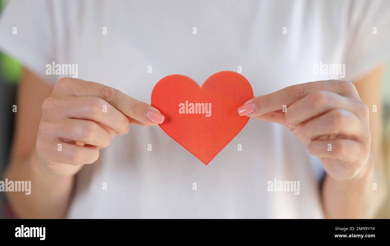 La donna tiene il cuore nelle sue mani davanti al petto. Foto Stock
