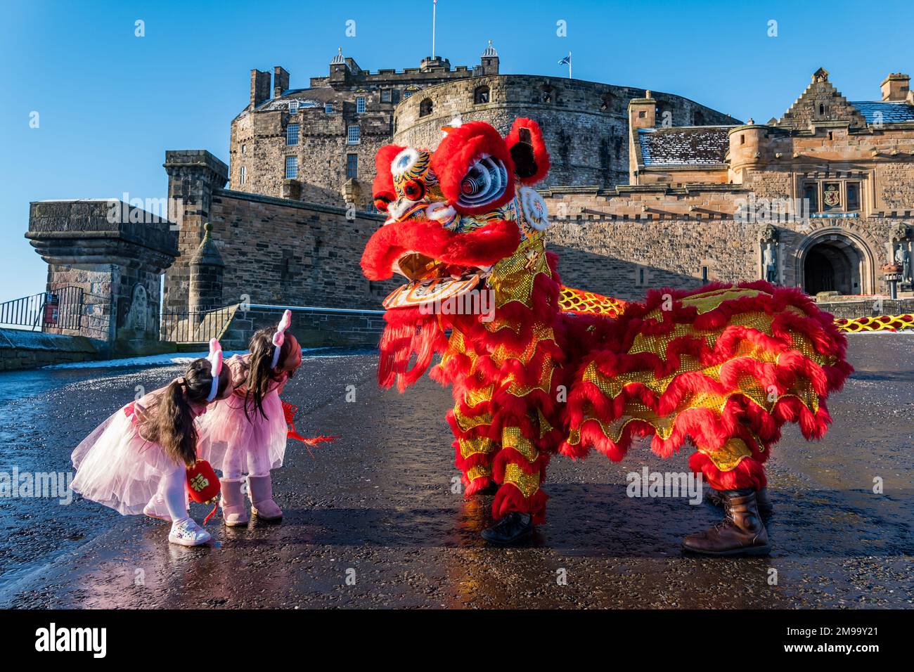 Giovani ragazze cinesi che indossano orecchie di coniglio intrattenuti da danzatori drago per celebrare il Capodanno cinese, (anno del coniglio), Castello di Edimburgo, Scozia, Regno Unito Foto Stock