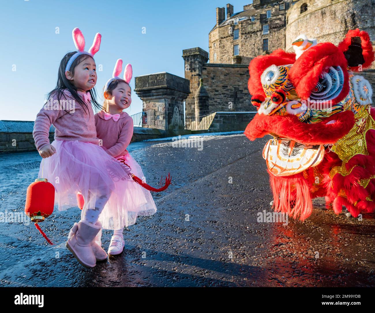 Giovani ragazze cinesi che indossano orecchie di coniglio intrattenuti da danzatori drago per celebrare il Capodanno cinese, (anno del coniglio), Castello di Edimburgo, Scozia, Regno Unito Foto Stock