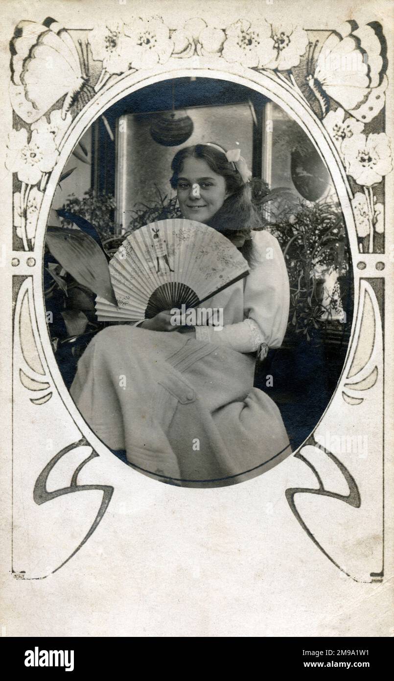 Una fotografia di una giovane ragazza sorridente incastonata in una cornice ovale art nouveau. Ha in mano un fan promozionale per Stower's Lime Juice Cordial! Foto Stock