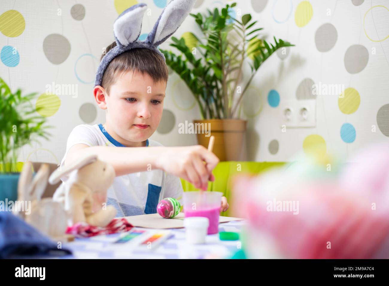 Buona Pasqua. Ragazzo in orecchie coniglietto tintura uovo colorato per la caccia di Pasqua Foto Stock