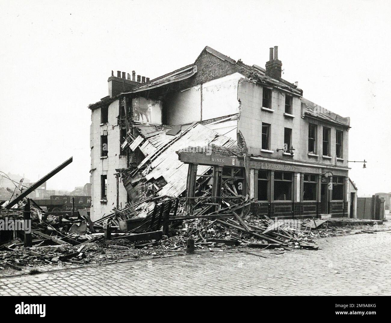 Fotografia di City Arms, Victoria Docks, Londra. Il lato principale della stampa (mostrato qui) raffigura: Vista del pub in fase di demolizione. Il retro della stampa (disponibile su richiesta) dettagli: Niente per il City Arms, Victoria Docks, Londra E16 1AH. A partire da luglio 2018 . Distrutta dall'azione nemica 1946 Foto Stock