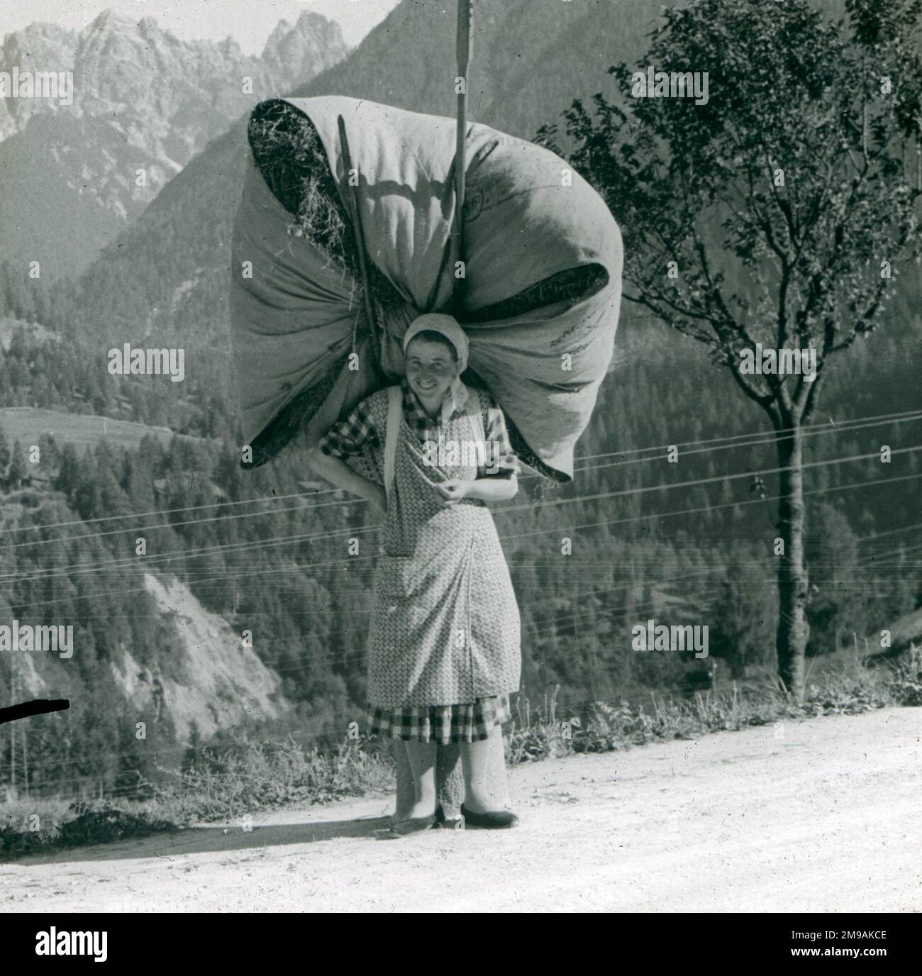 Donna spagnola al bordo della strada che trasporta un pacchetto voluminoso di Hay, Spagna. Foto Stock