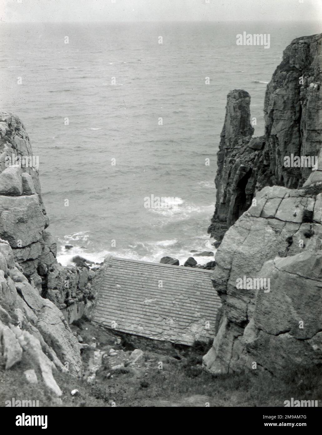 Incastonata in una nicchia, in parte giù per la scogliera a Castlemartin, è l'antica chiesa di St Govan, Pembrokeshire, Galles del Sud. Foto Stock