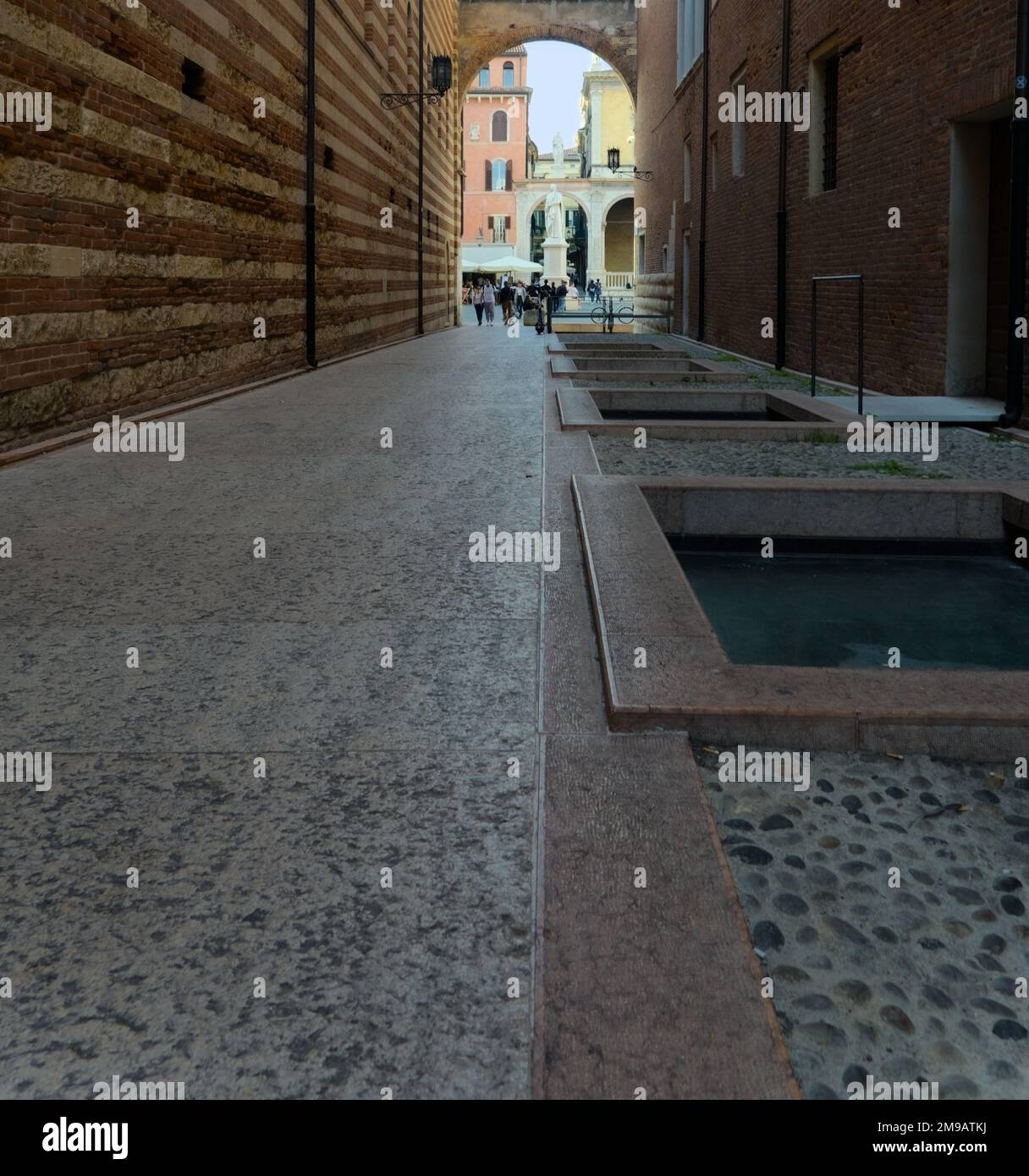 Un vicolo con pavimento in marmo conduce ad una porta ad arco. Foto Stock