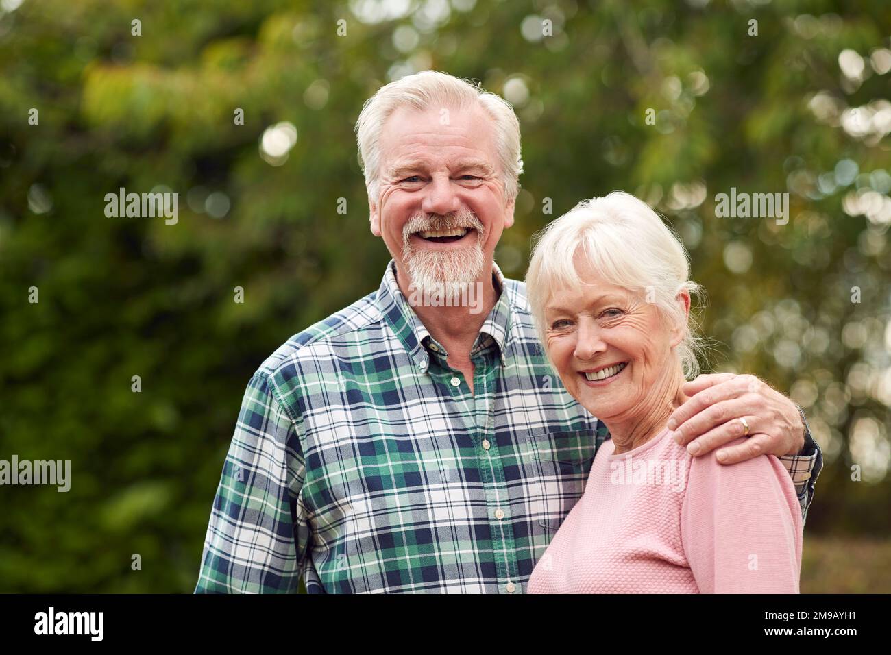 Ritratto di amorevole pensionato Senior Couple abbracciando all'aperto in campagna o giardino insieme Foto Stock