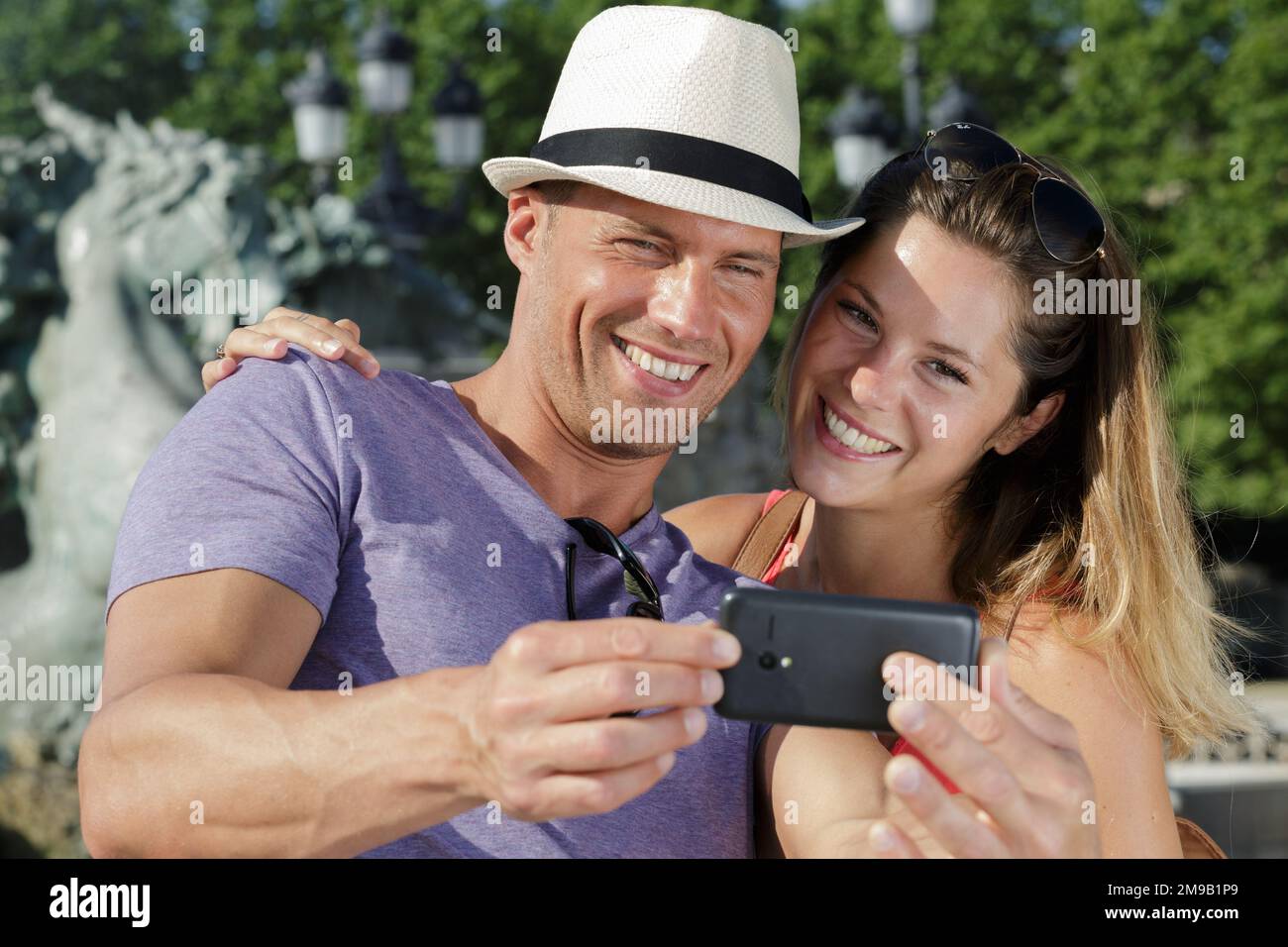 giovane coppia sorridente che prende selfie all'aperto Foto Stock