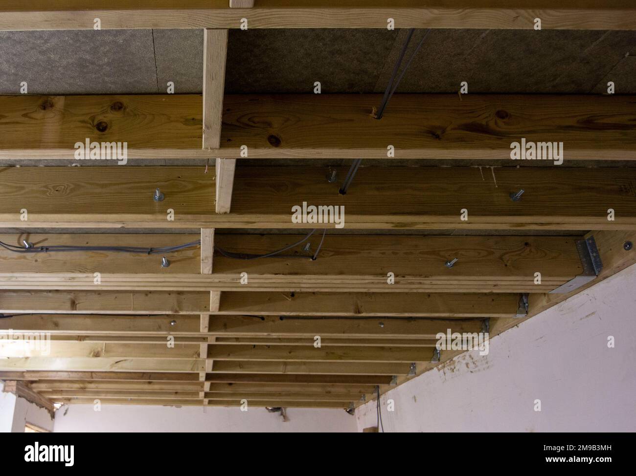 Nuove travi a soffitto con componenti elettrici fissi prima che il soffitto in cartongesso venga montato durante la ristrutturazione di una casa Foto Stock