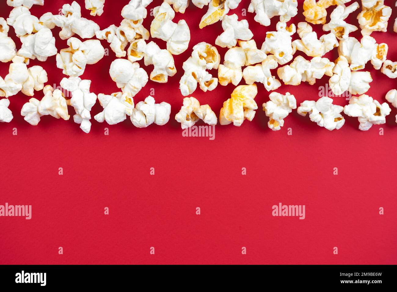 Saporito popcorn formaggio sparso isolato su sfondo rosso. Vista dall'alto, piatto, banner, sfondo, bordo con spazio per la copia Foto Stock