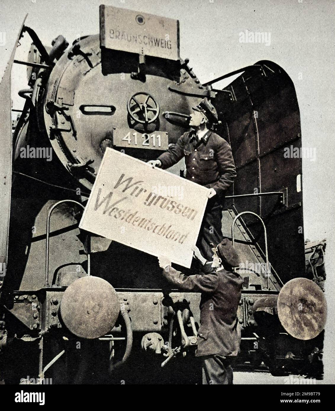 Fotografia che mostra l'equipaggio di una locomotiva di Berlino Ovest che presenta il banner "saluti alla Germania Occidentale" sulla parte anteriore del treno alla fine del blocco di Berlino, maggio 1949. Questo treno stava per fare il suo primo viaggio da Berlino Ovest alla Germania Occidentale, passando per la Germania Est, per un anno. Tra l'aprile 1948 e il maggio 1949 Josef Stalin, leader dell'URSS, ha imposto un blocco fondiario sulle forniture dall'Europa occidentale a Berlino Ovest. In risposta, i governi britannico e americano hanno organizzato un enorme ponte aereo per fornire cibo e altri beni essenziali ai 2,5 milioni di abitanti di Berlino Ovest. Foto Stock