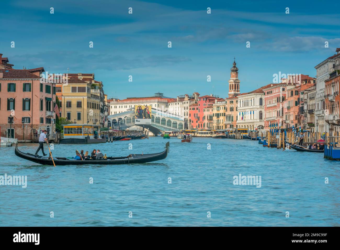 Gondoliere veneziano con la sua Gondola e ospiti sul Canal Grande, con sullo sfondo il famoso Ponte di Rialto Foto Stock