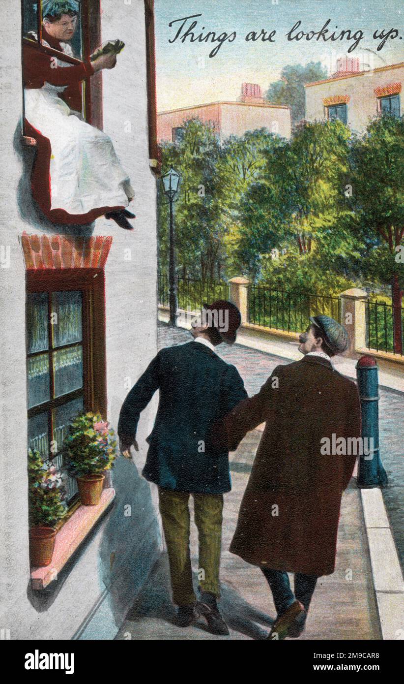 "Le cose stanno guardando in alto" - due uomini di passaggio sono felici di vedere che le loro attenzioni sono state avvistate da una cameriera che pulisce le finestre al piano superiore di una proprietà a lato della strada Foto Stock