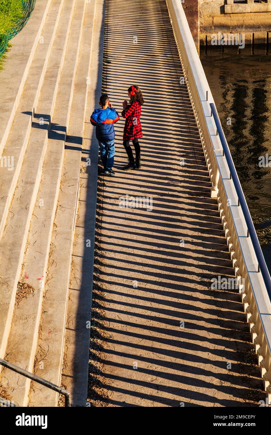 Ragazzo e ragazza che saltano felicemente lungo il sentiero di pietra illuminato dal sole; Fairmount Water Works; Philadelphia; Pennsylvania; USA Foto Stock