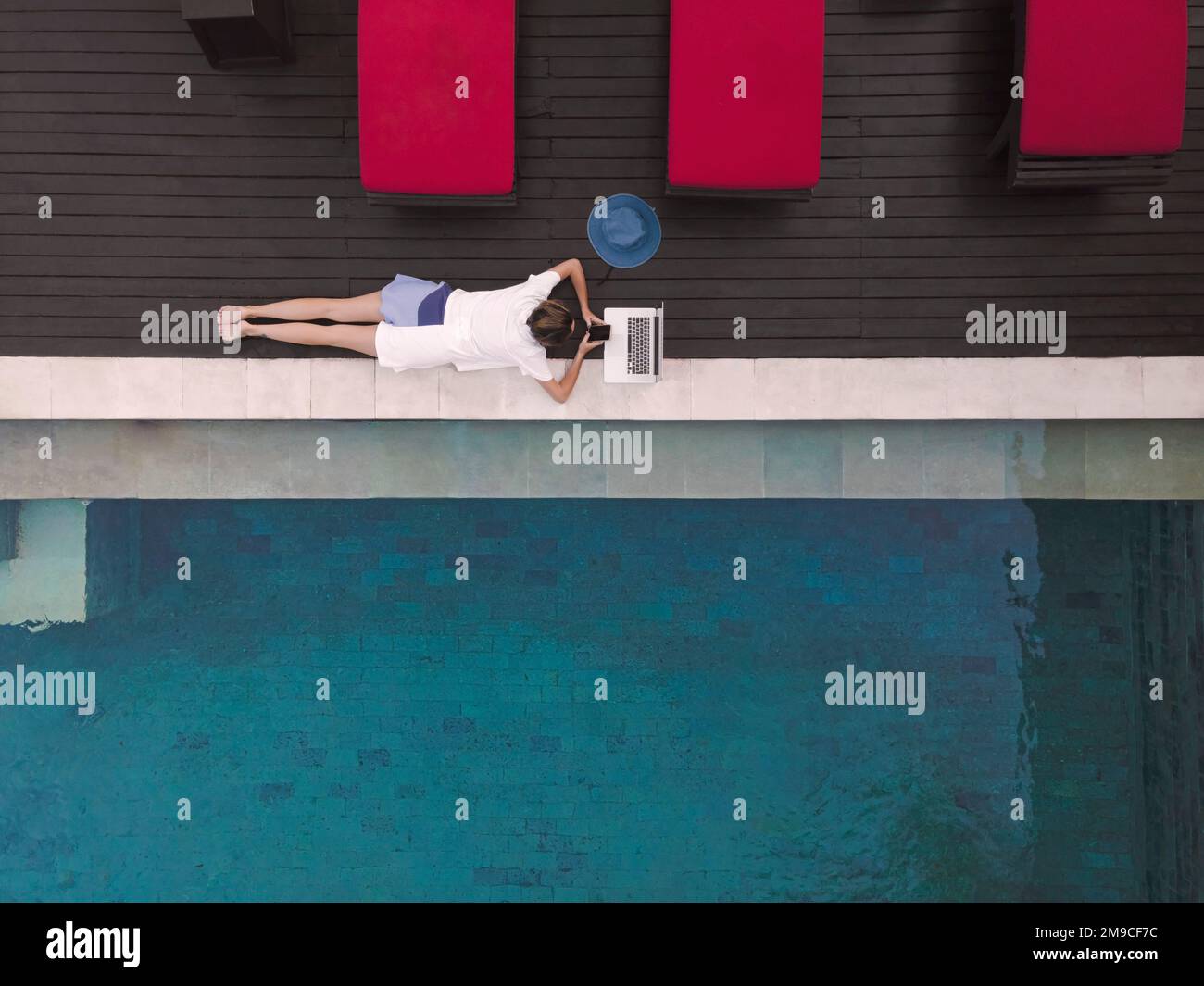 Vista aerea giovane donna con computer portatile vicino alla piscina Foto Stock