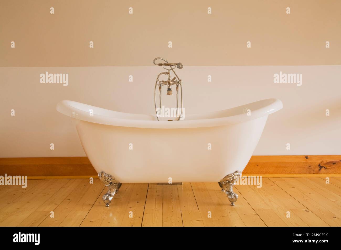 Vasca da bagno indipendente bianca con poggiapiedi nella camera da letto principale al piano superiore all'interno di una cabina in legno fresato. Foto Stock